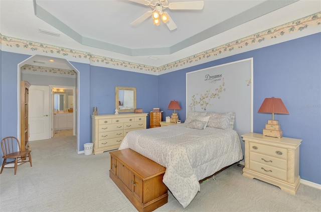 bedroom with a tray ceiling, light colored carpet, and ceiling fan