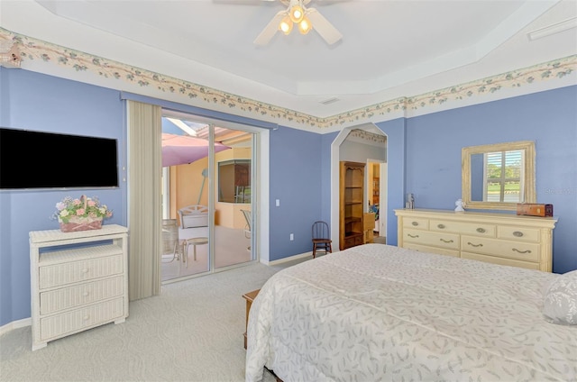 carpeted bedroom featuring ceiling fan, a tray ceiling, and access to outside