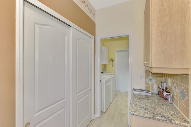 clothes washing area with cabinets, independent washer and dryer, and light hardwood / wood-style floors