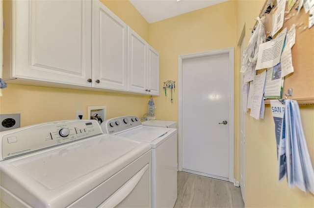 washroom with cabinets, washing machine and clothes dryer, and light wood-type flooring