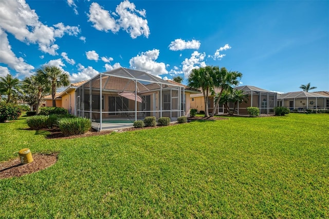 rear view of property with a yard and glass enclosure