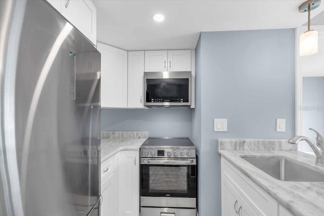 902 Gibbs Rd Unit 181, Venice, FL 34285 - kitchen with stainless steel appliances, white cabinetry, hanging light fixtures, recessed lighting, and light stone countertops