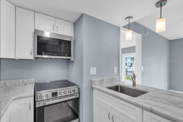 902 Gibbs Rd Unit 181, Venice, FL 34285 - kitchen with appliances with stainless steel finishes, white cabinetry, hanging light fixtures, and light stone counters