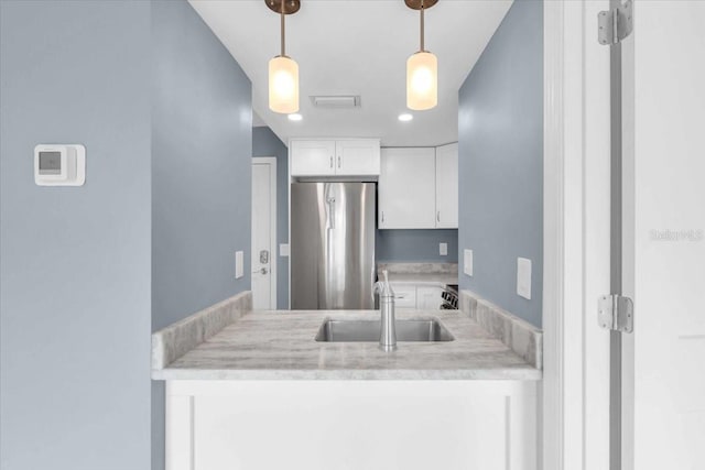 902 Gibbs Rd Unit 181, Venice, FL 34285 - kitchen with stainless steel fridge, white cabinetry, light countertops, and hanging light fixtures