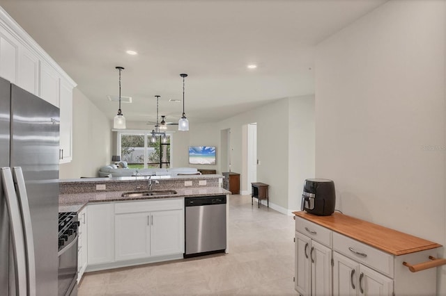 kitchen with appliances with stainless steel finishes, sink, white cabinetry, and kitchen peninsula