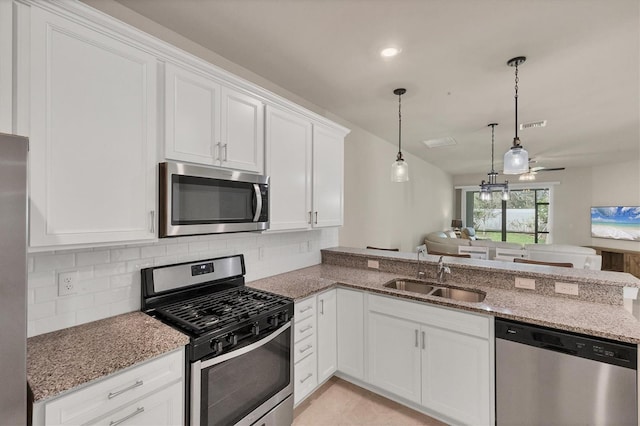 kitchen with stainless steel appliances, decorative light fixtures, sink, white cabinetry, and kitchen peninsula