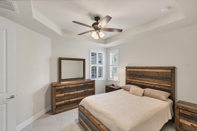 tiled bedroom featuring ceiling fan and a raised ceiling