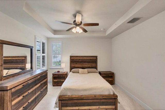 tiled bedroom featuring a raised ceiling and ceiling fan