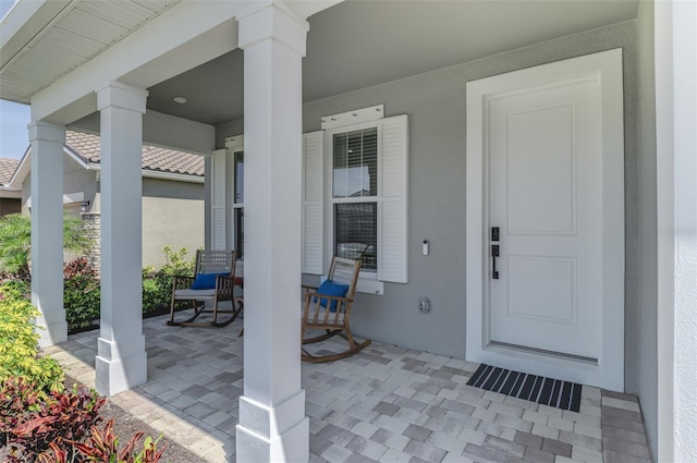 view of exterior entry featuring covered porch and stucco siding