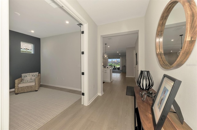 corridor featuring light wood-style flooring, visible vents, baseboards, and recessed lighting