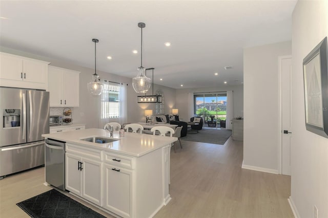 kitchen featuring stainless steel appliances, a sink, white cabinetry, light countertops, and light wood-type flooring