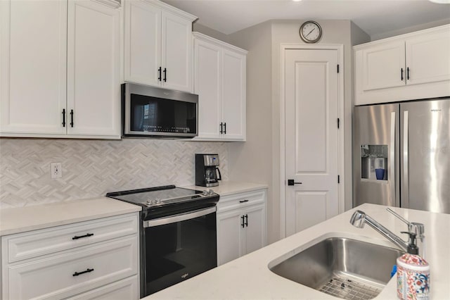 kitchen with tasteful backsplash, light countertops, appliances with stainless steel finishes, white cabinets, and a sink