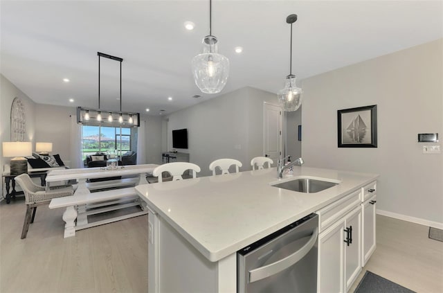 kitchen with a kitchen island with sink, a sink, white cabinetry, open floor plan, and stainless steel dishwasher