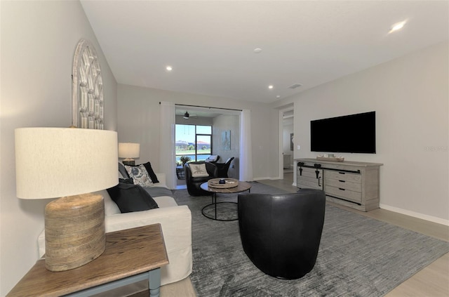 living area featuring baseboards, wood finished floors, and recessed lighting