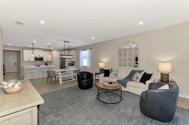 living room featuring light wood finished floors, visible vents, and recessed lighting