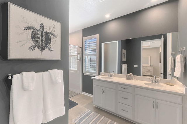 bathroom with double vanity, a shower stall, a sink, and wood finished floors