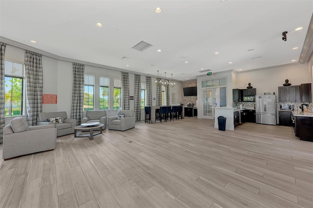 living area featuring visible vents, ornamental molding, an inviting chandelier, light wood-style floors, and recessed lighting