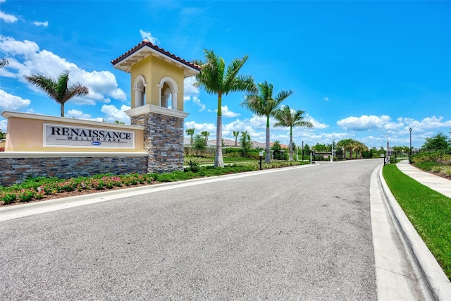 view of road featuring sidewalks, curbs, and a gated entry