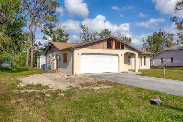 view of front of home with an attached garage, driveway, a front lawn, and stucco siding