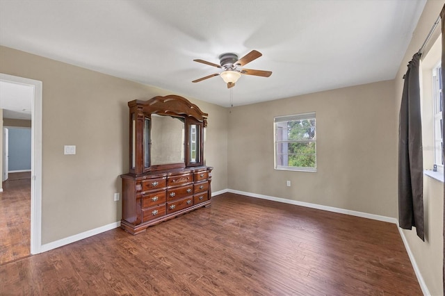 unfurnished bedroom featuring ceiling fan, baseboards, and dark wood finished floors