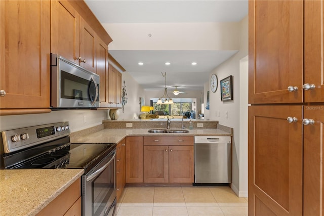 kitchen with brown cabinets, light stone countertops, stainless steel appliances, and a sink