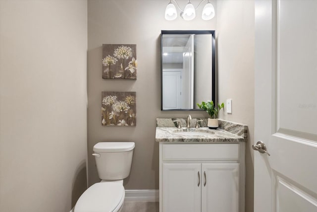 half bathroom with baseboards, toilet, and vanity