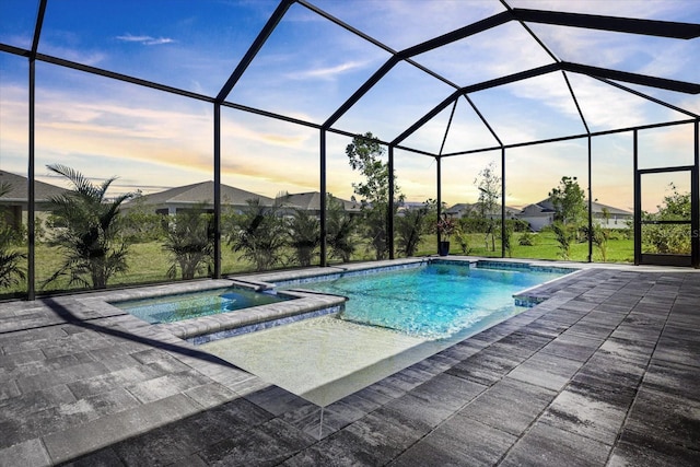 view of swimming pool with glass enclosure, a pool with connected hot tub, and a patio