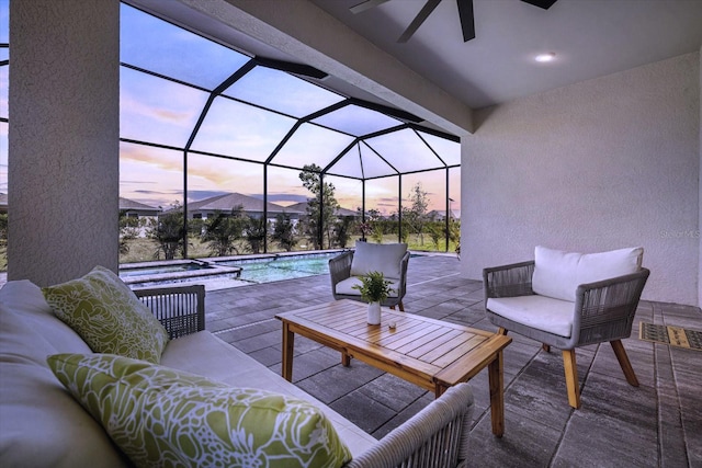 patio terrace at dusk with a lanai, an outdoor pool, and an outdoor hangout area