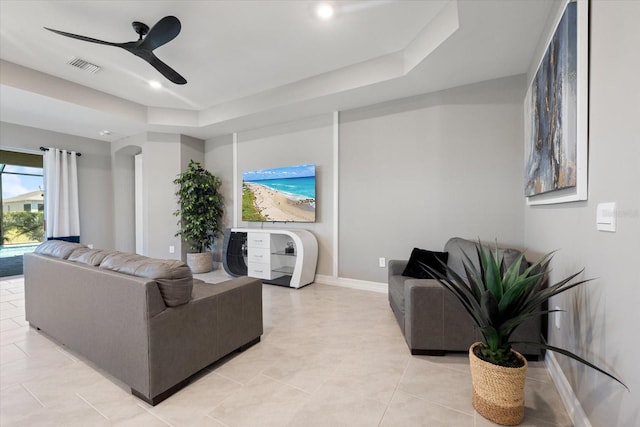 living room with visible vents, a ceiling fan, arched walkways, light tile patterned flooring, and baseboards