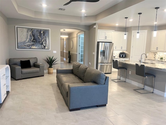 living room with a ceiling fan, visible vents, baseboards, light tile patterned flooring, and arched walkways