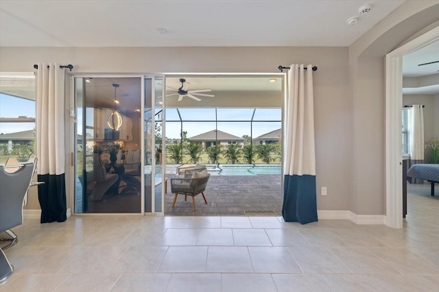 entryway featuring tile patterned floors, a ceiling fan, baseboards, and a sunroom