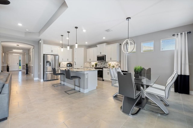 dining room featuring visible vents, baseboards, light tile patterned flooring, recessed lighting, and arched walkways