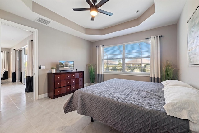 bedroom with visible vents, baseboards, light tile patterned flooring, a raised ceiling, and ceiling fan