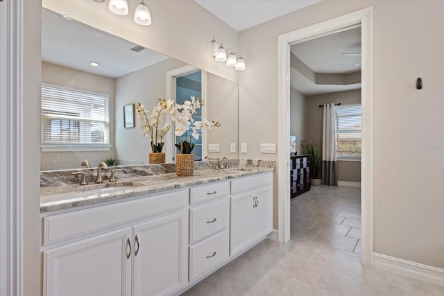 full bathroom featuring double vanity, visible vents, baseboards, and a sink