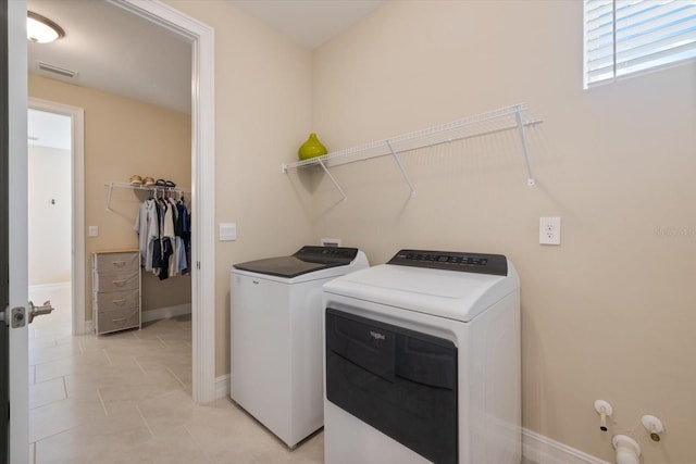 laundry area featuring visible vents, baseboards, washing machine and dryer, light tile patterned floors, and laundry area