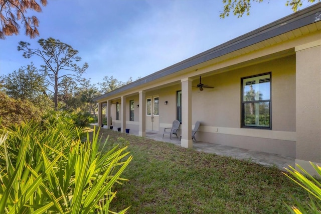 entrance to property featuring stucco siding, ceiling fan, and a patio area