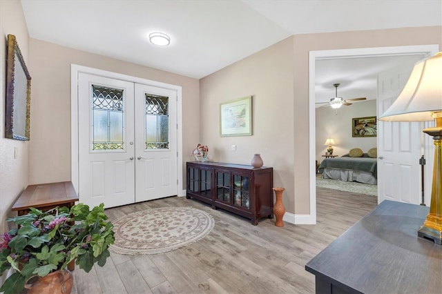 foyer entrance featuring baseboards, ceiling fan, vaulted ceiling, light wood-style floors, and french doors