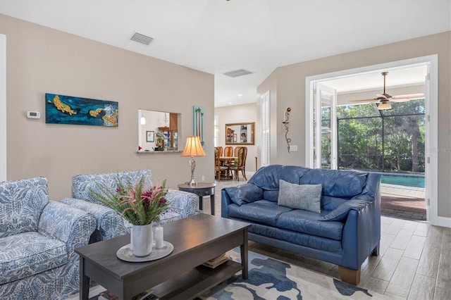 living area featuring visible vents, baseboards, ceiling fan, and wood finished floors