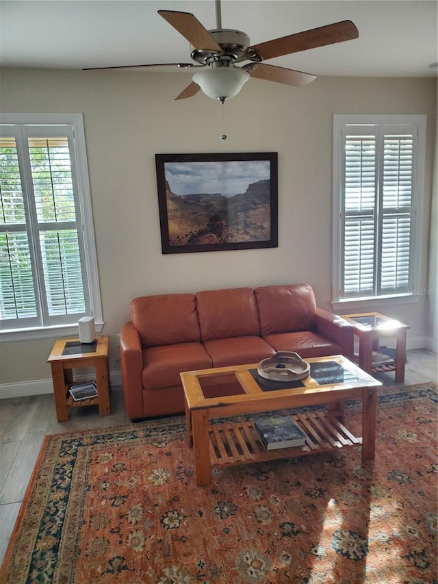 living area featuring wood finished floors, a ceiling fan, baseboards, and a wealth of natural light