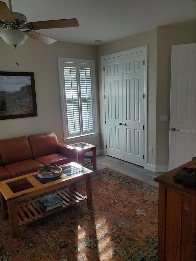 living room with baseboards and ceiling fan