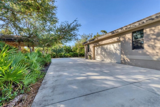 view of property exterior with a garage, concrete driveway, and stucco siding