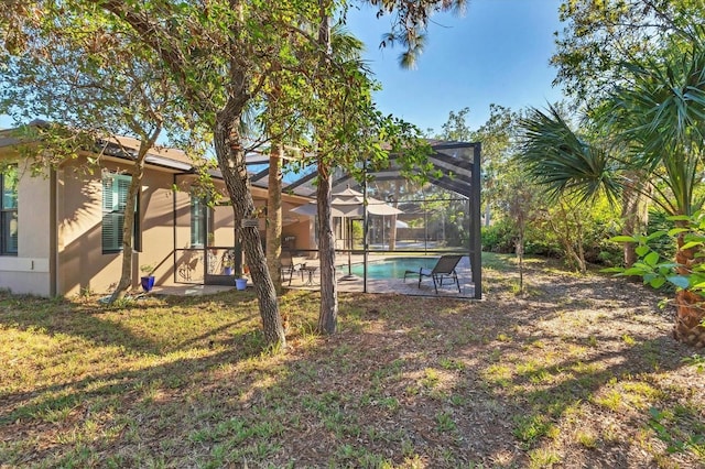 view of yard featuring an outdoor pool, glass enclosure, and a patio area