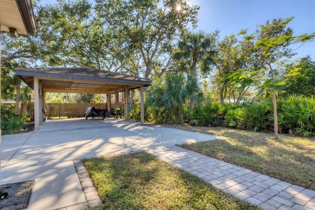 view of yard with a carport, driveway, and fence