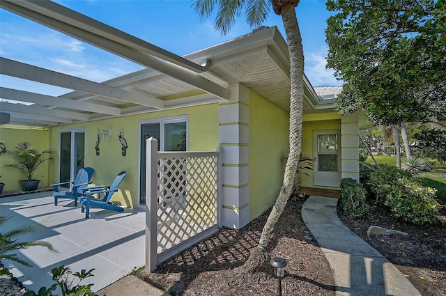 entrance to property featuring a patio and stucco siding