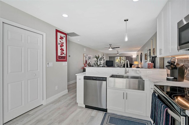 kitchen with stainless steel appliances, visible vents, white cabinets, a sink, and a peninsula