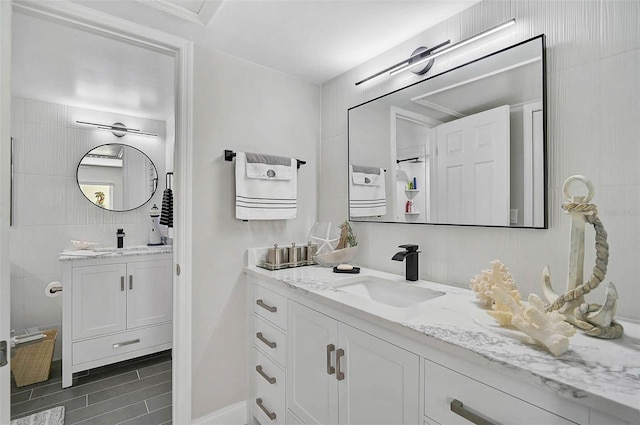 bathroom with tile walls, two vanities, a sink, and wood finished floors