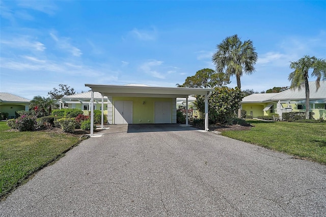 view of front of house featuring driveway, an attached carport, and a front yard