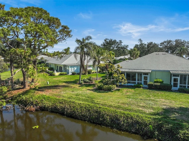 back of house with a yard, a water view, and a sunroom