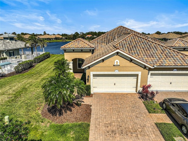 view of front facade with decorative driveway, a front yard, a tile roof, and stucco siding