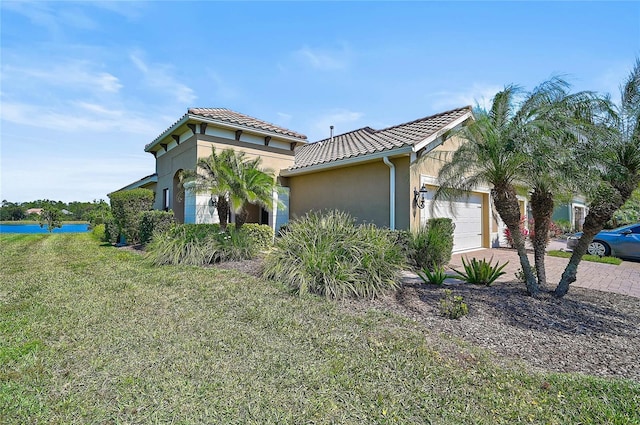 mediterranean / spanish home featuring a garage, decorative driveway, a tiled roof, and stucco siding